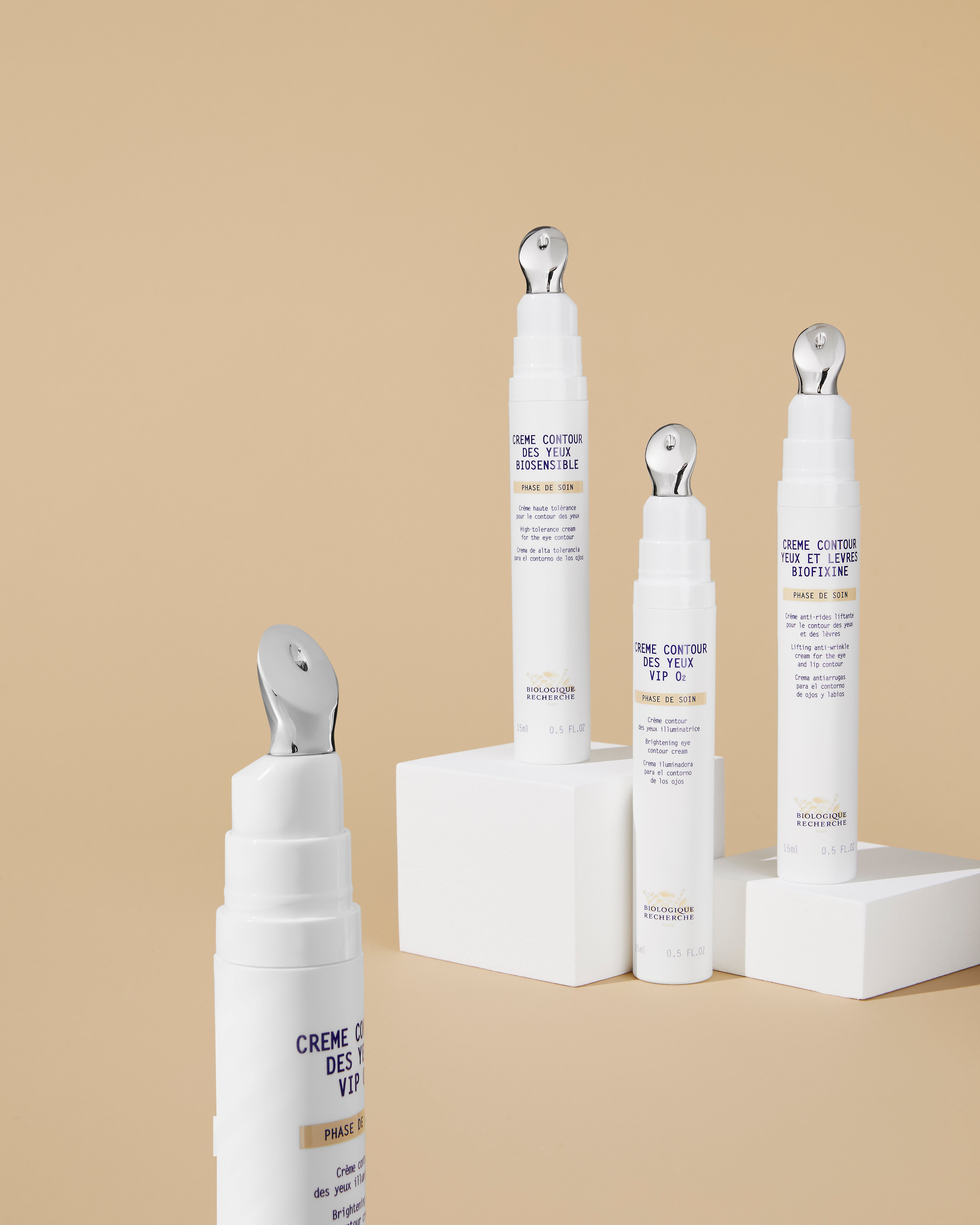 White cream tubes with silver applicator tips for eye care, labeled Crème Contour des Yeux VIP O2, displayed on beige.