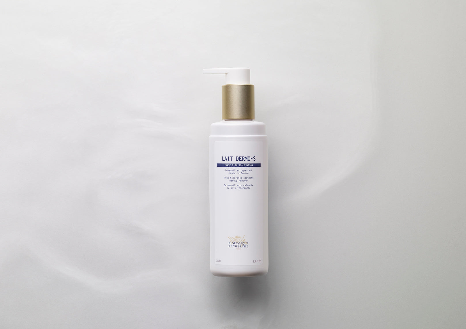 White cylindrical bottle of Lait Dermo-S with gold pump dispenser and minimal blue text on label.