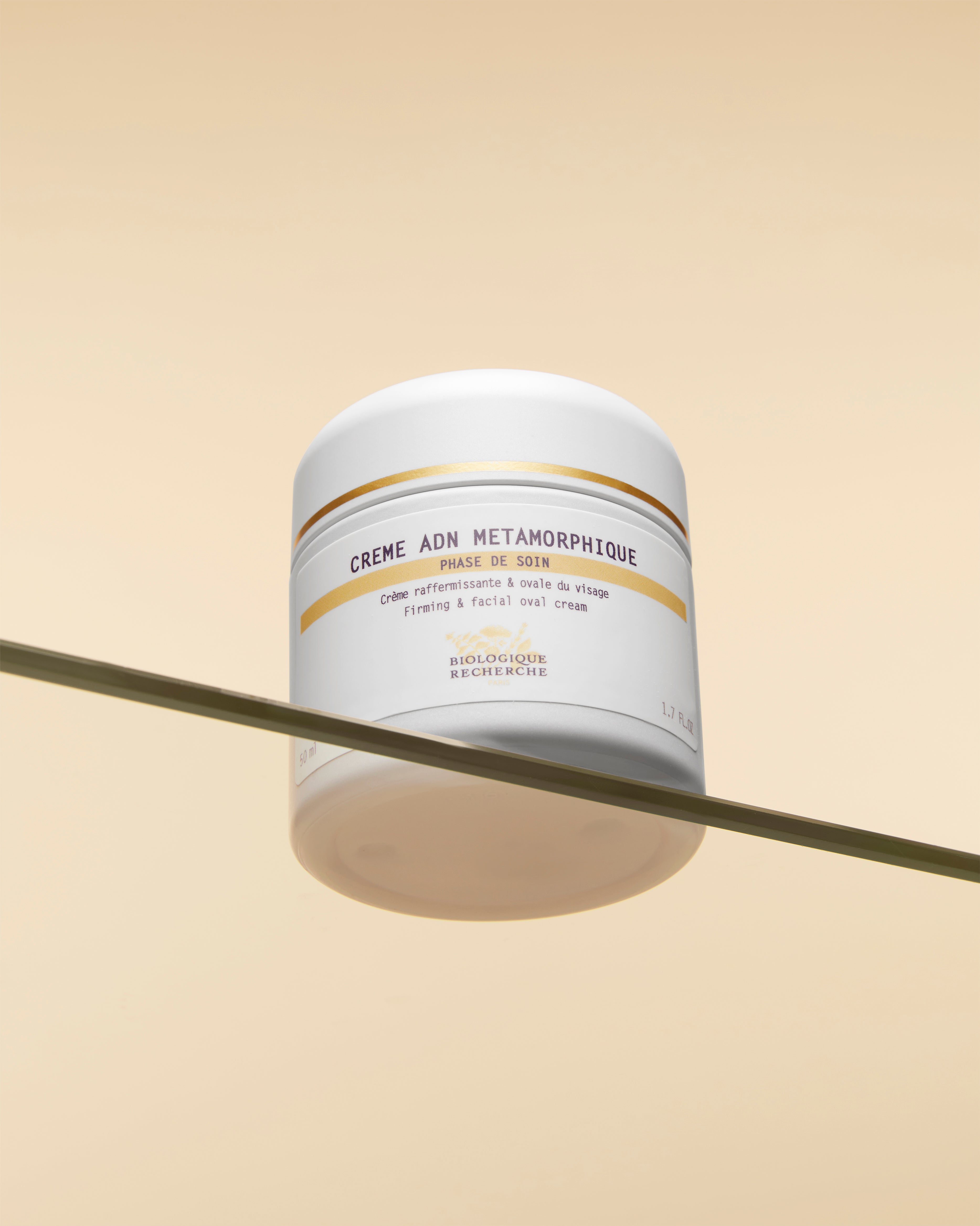White jar of Crème PTO Métamorphique with yellow and black text on a glass shelf against a beige background.