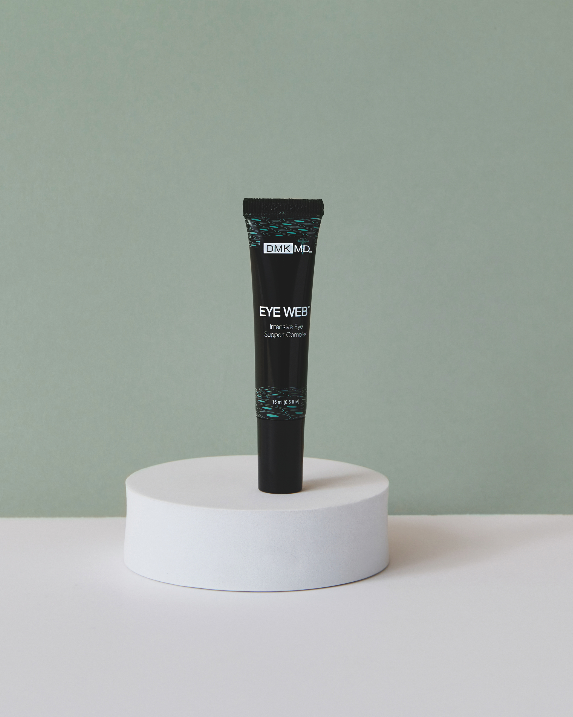 Black tube of MD Eye Web Crème with white text on a round white pedestal against a gray background.