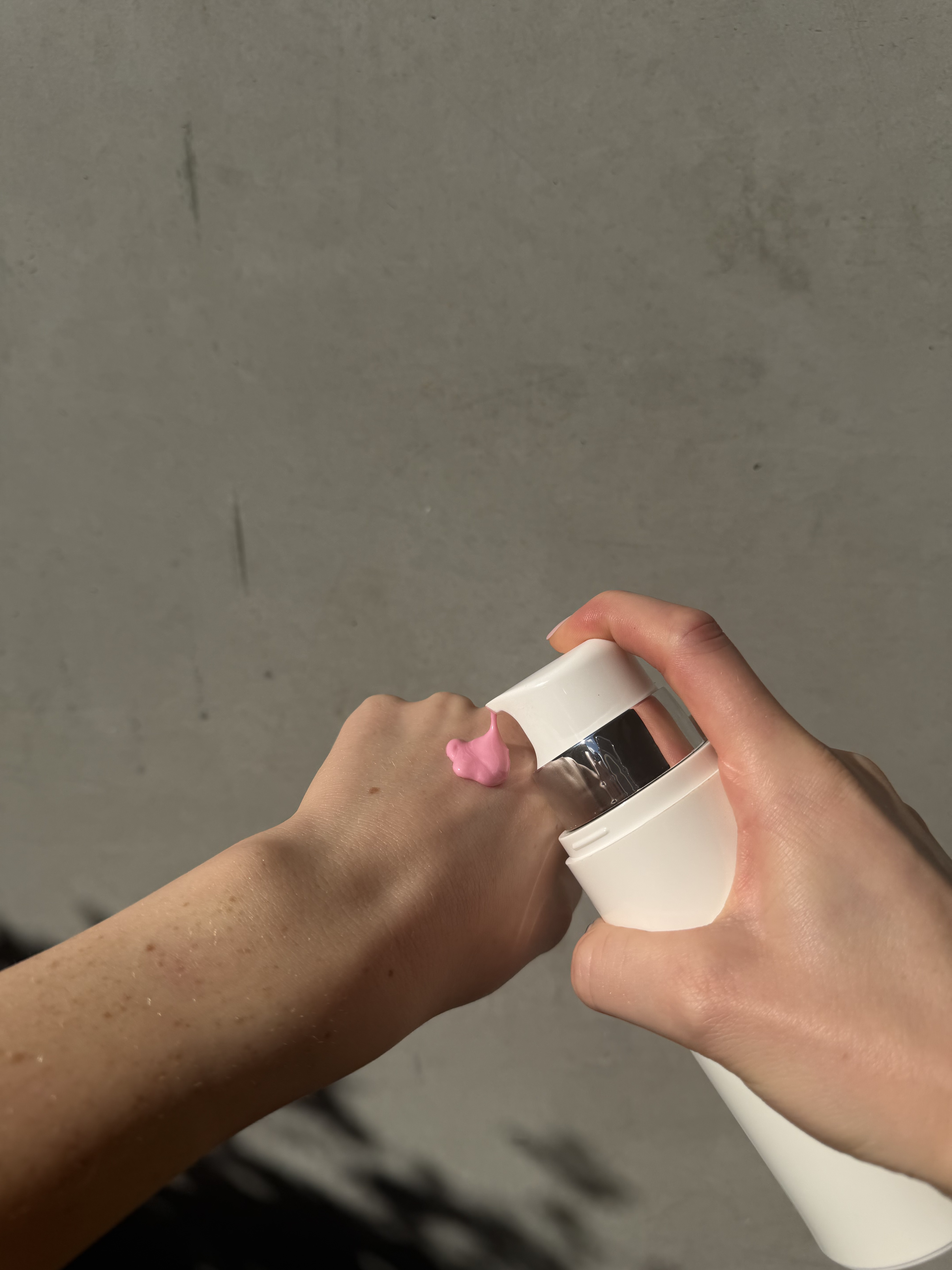 Pink Magic Vitamin B12 Cream being dispensed onto the back of the hand, showing its signature pink colour.